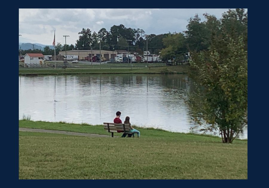 Two people sitting on a bench overlooking a pond in an East Tennessee park