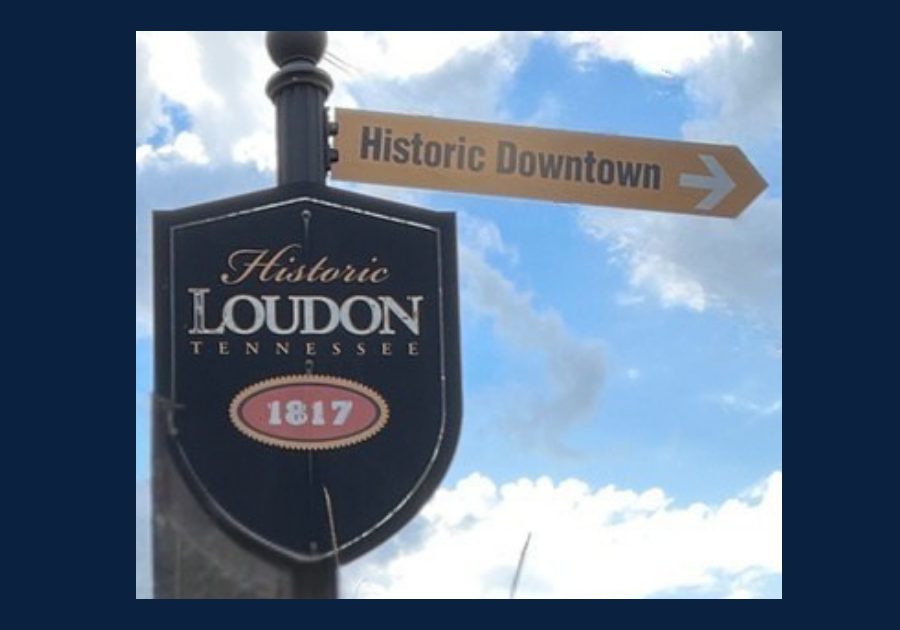 Historic Loudon Tennessee downtown sign with 1817 emblem and arrow pointing toward Historic Downtown under blue sky.
