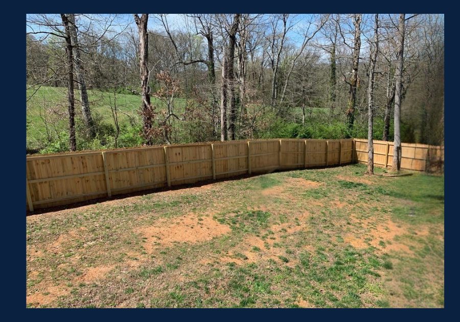 Backyard with wooden privacy fence and wooded area behind a home in East Tennessee