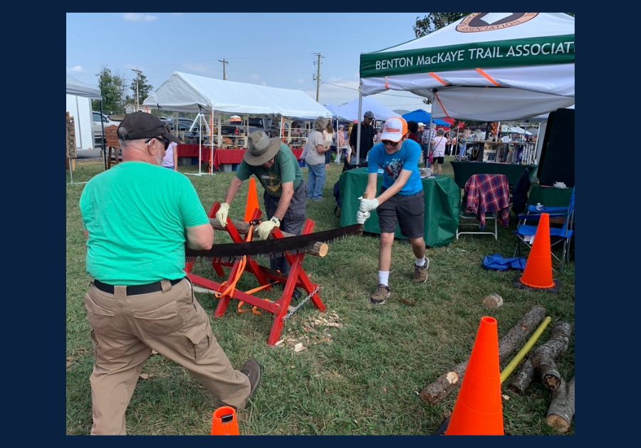 People demonstrating crosscut saw woodworking at a community event in East Tennessee